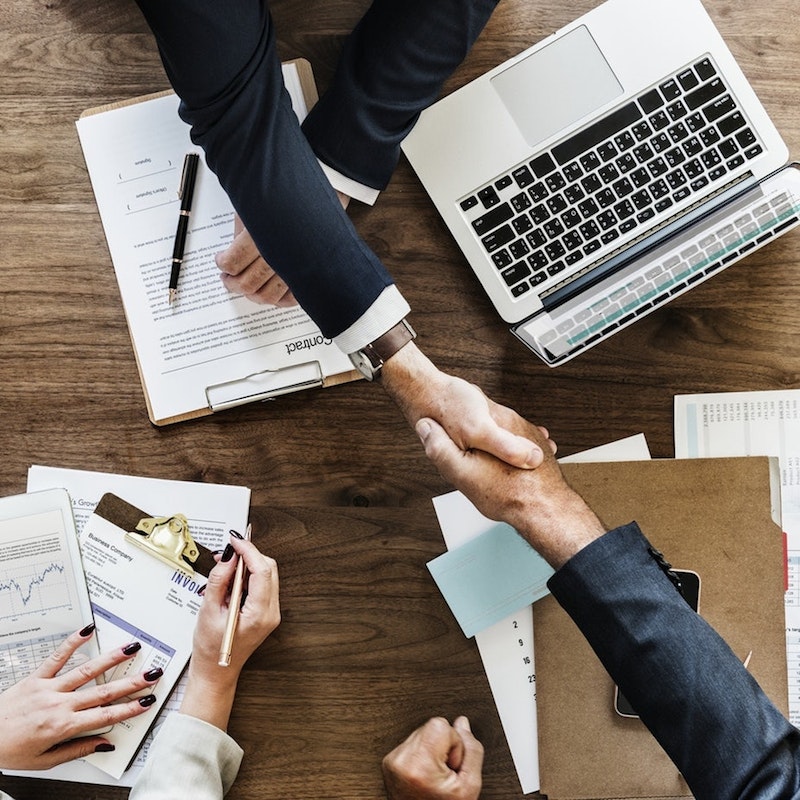 Two businesspeople shaking hands across a table